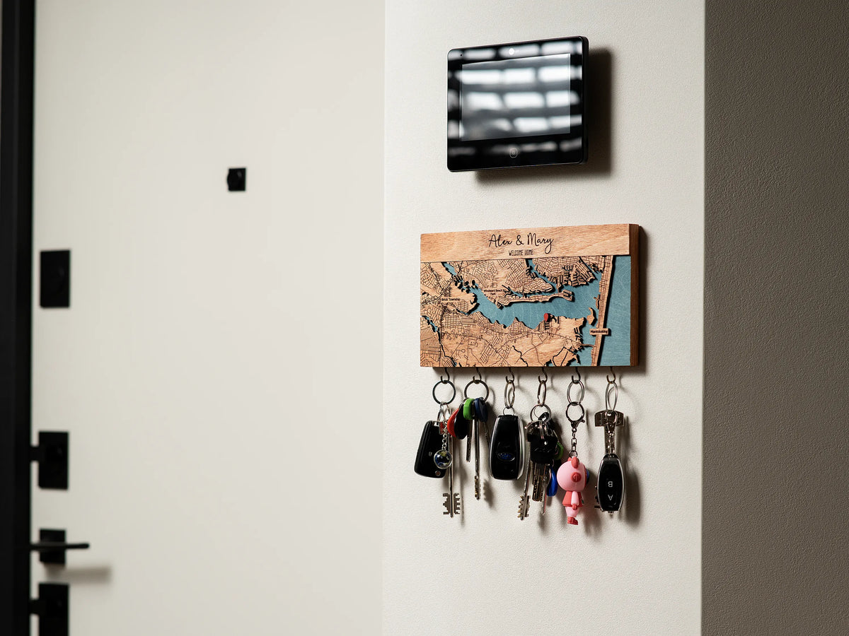 Personalized wooden key holder with hooks and custom map design displayed in a modern entryway with keys hanging below.