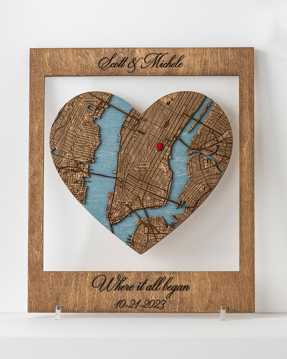 Heart-shaped wooden map cutout with engraved names and date on a white background