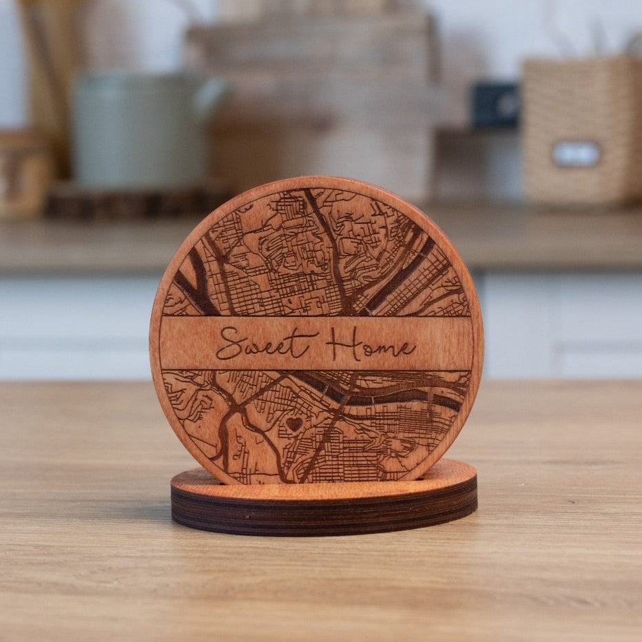 Wooden coaster with engraved map design and 'Sweet Home' text on a wooden surface.