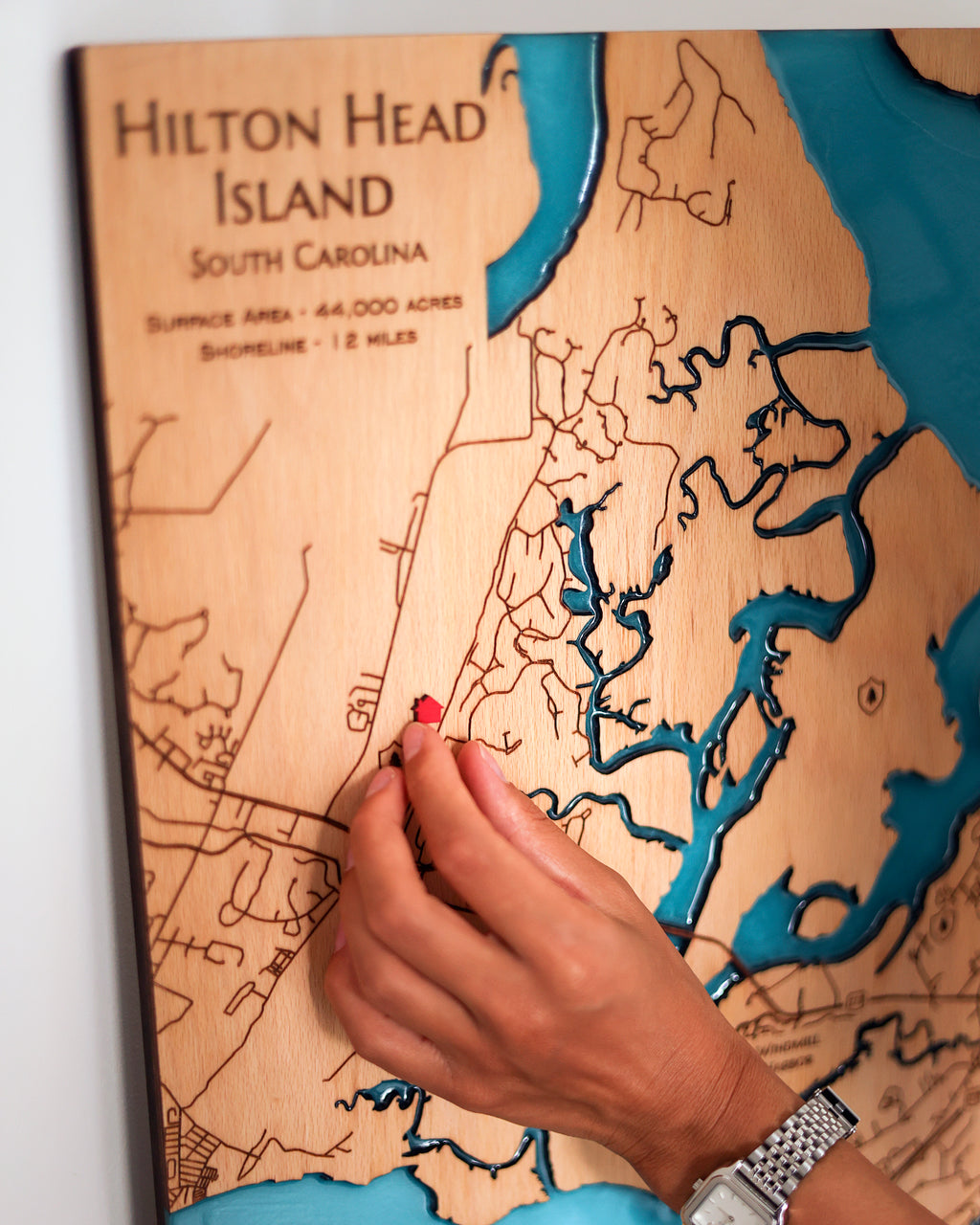 Wooden map of Hilton Head Island, South Carolina with a hand pointing to a location.