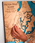 Wooden map of Hilton Head Island, South Carolina with a hand pointing to a location.