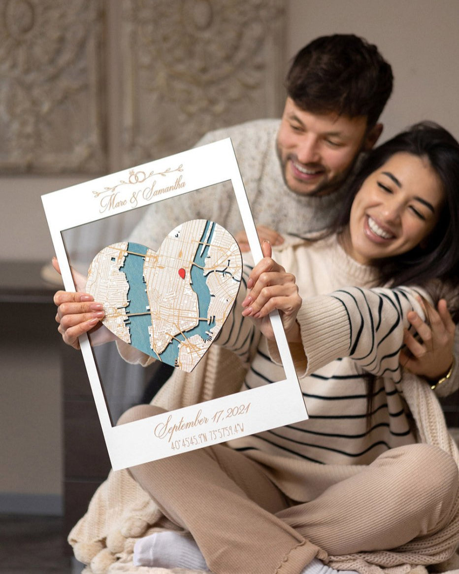 Couple holding a map of their wedding location in a decorative frame.