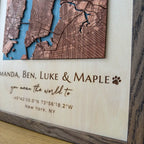Close-up of engraved names and coordinates on personalized layered wood map frame, premium wood detail
