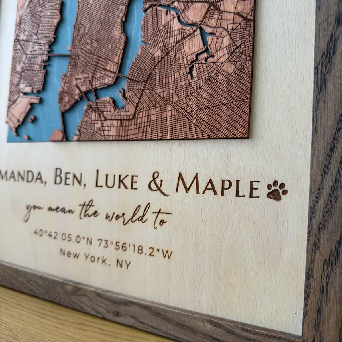 Close-up of engraved names and coordinates on personalized layered wood map frame, premium wood detail
