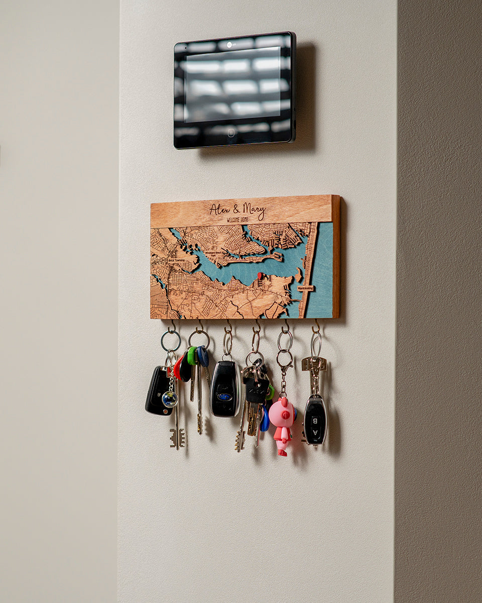 Key holder with keys attached to a wall, featuring a decorative wooden panel with a map design.