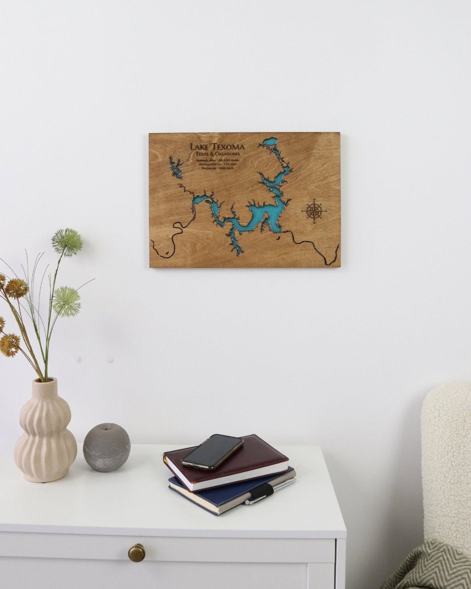 Wooden map of Lake Texoma on a wall above a white cabinet with decorative items.