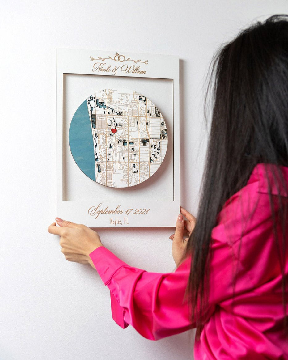 Person holding a framed personalized map on a white wall