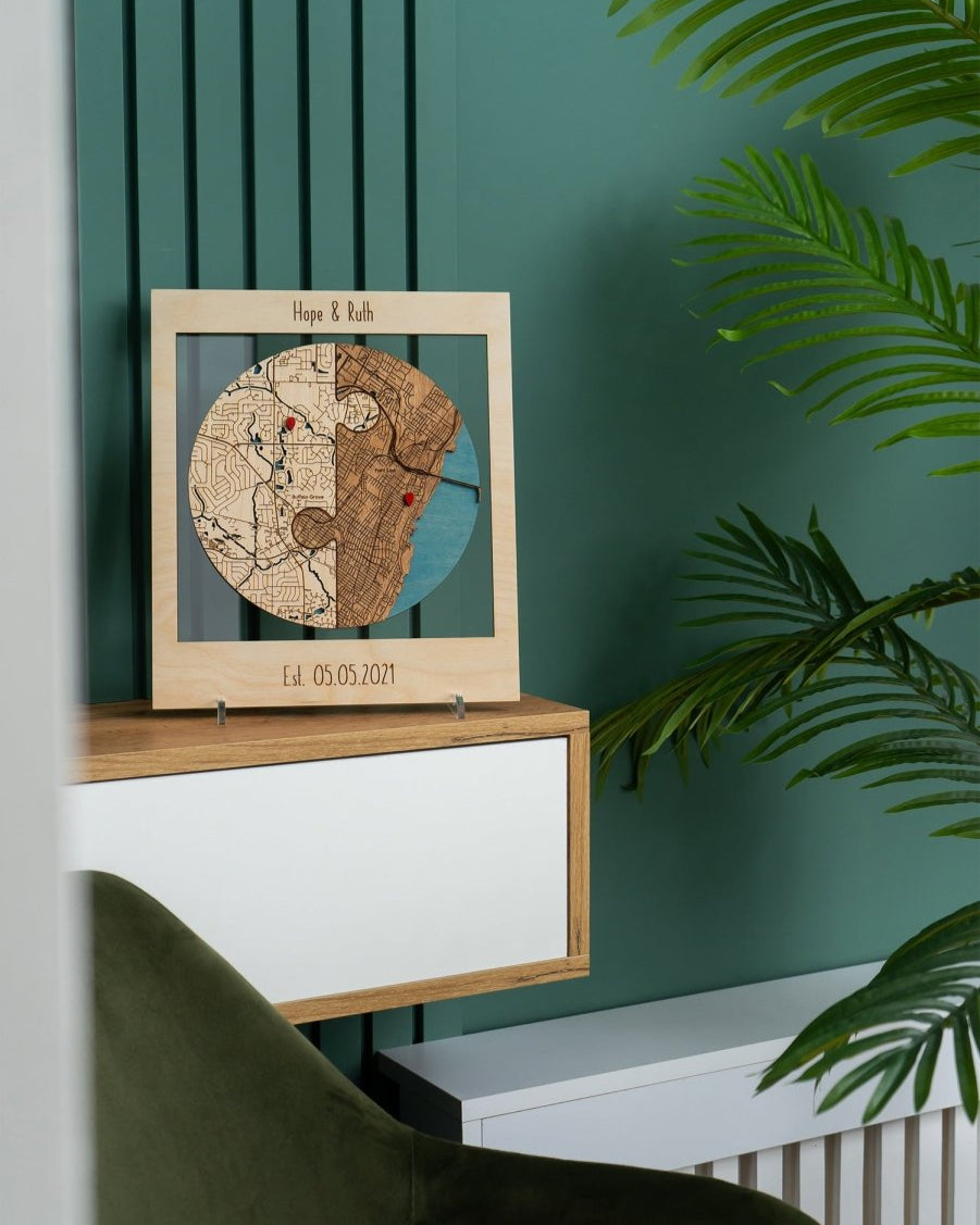 Wooden map decoration on a stand against a green wall with a plant in the foreground