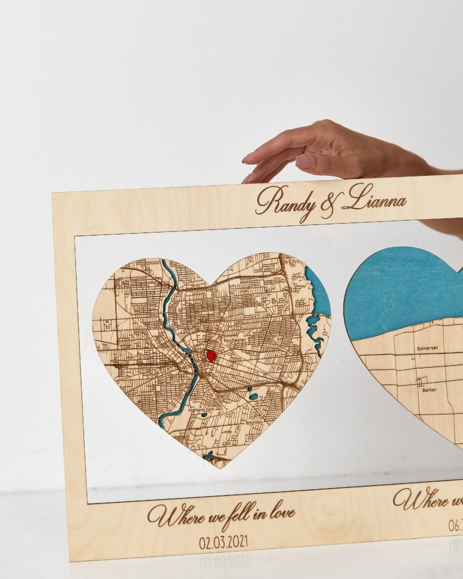 Heart-shaped wooden map with engraved text, held by a hand on a white background