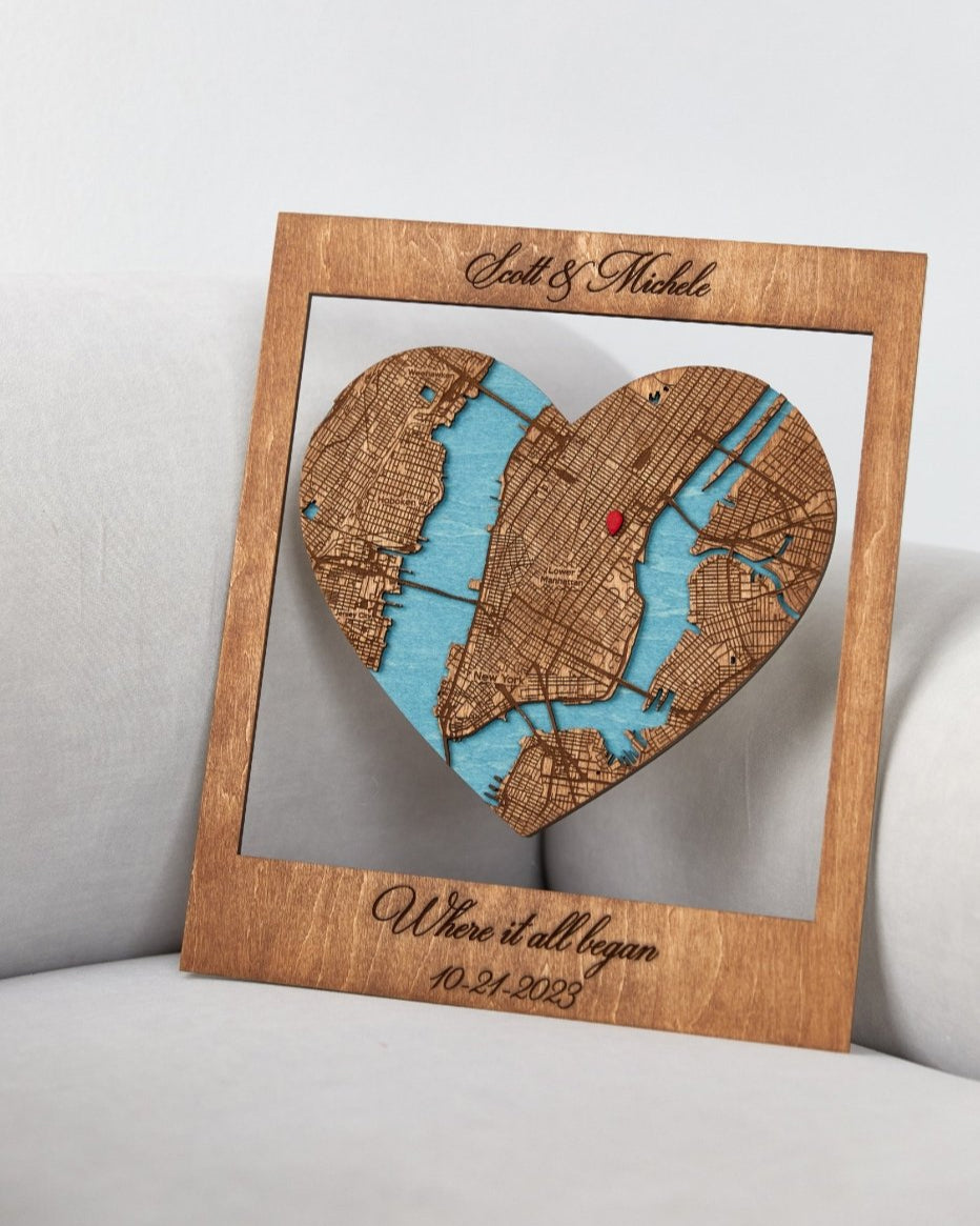 Wooden heart-shaped map cutout with engraved text on a light gray background