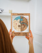 Person holding a wooden framed map with two locations marked, against a white background
