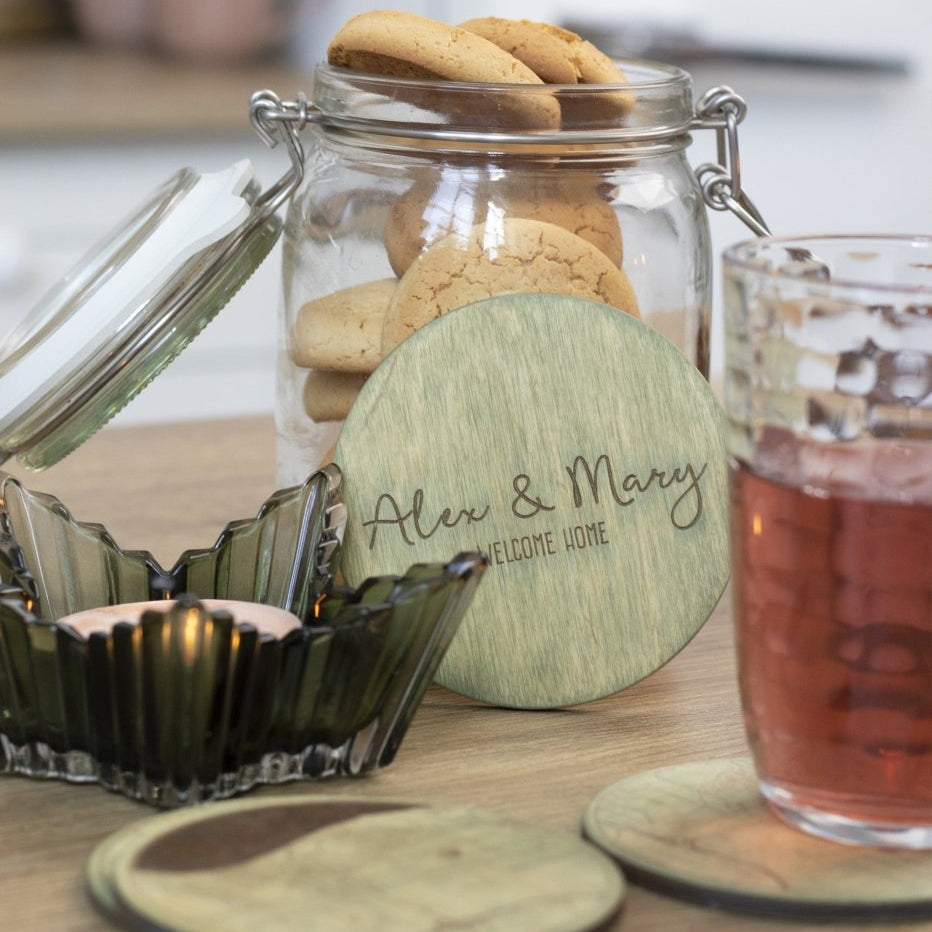 Glass jar with cookies, a glass of tea, and coasters on a table.