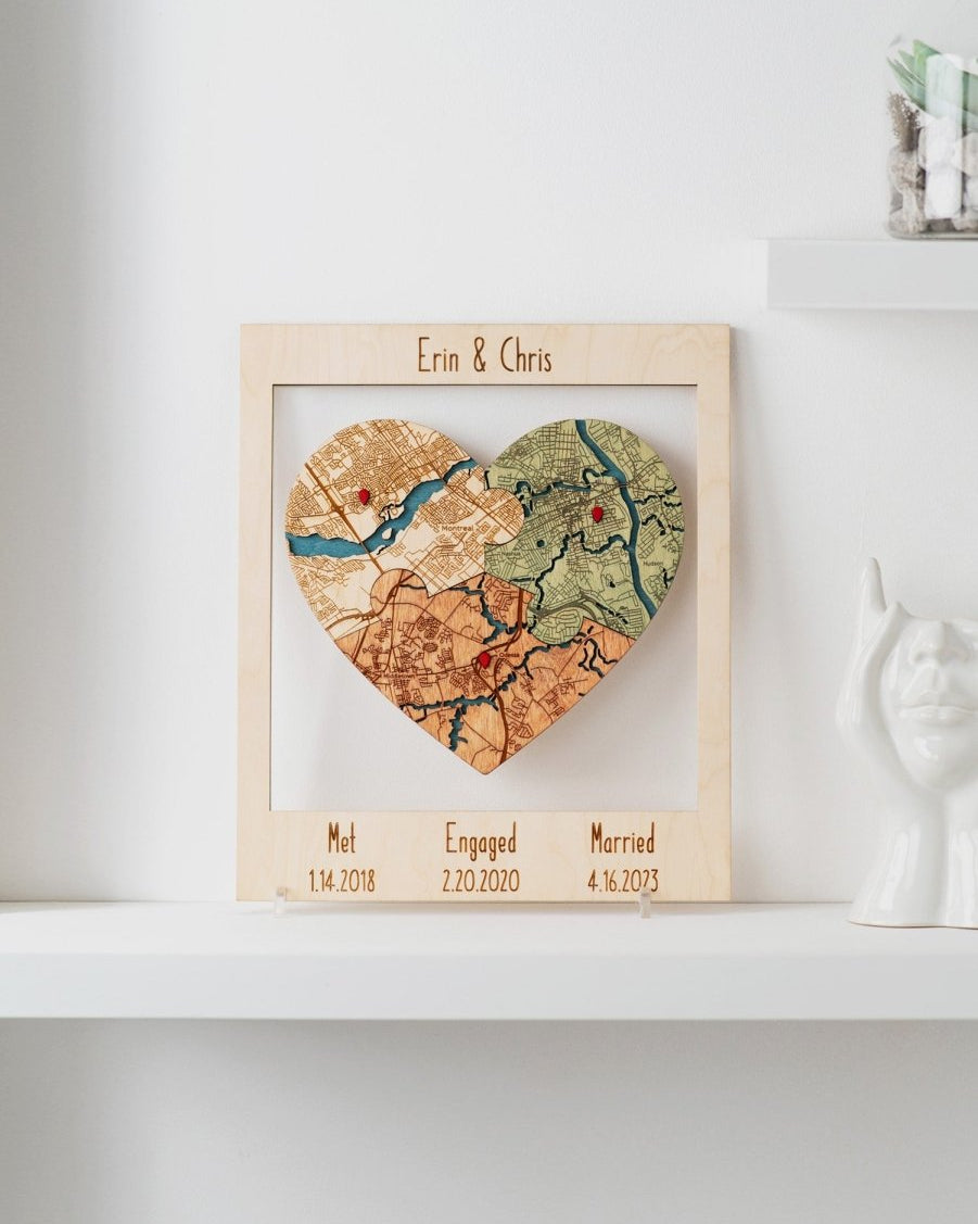 Heart-shaped map in a wooden frame with engraved dates on a white shelf.