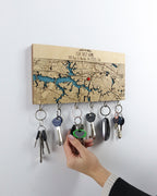 Key holder with keys attached to a map-themed board on a white wall.