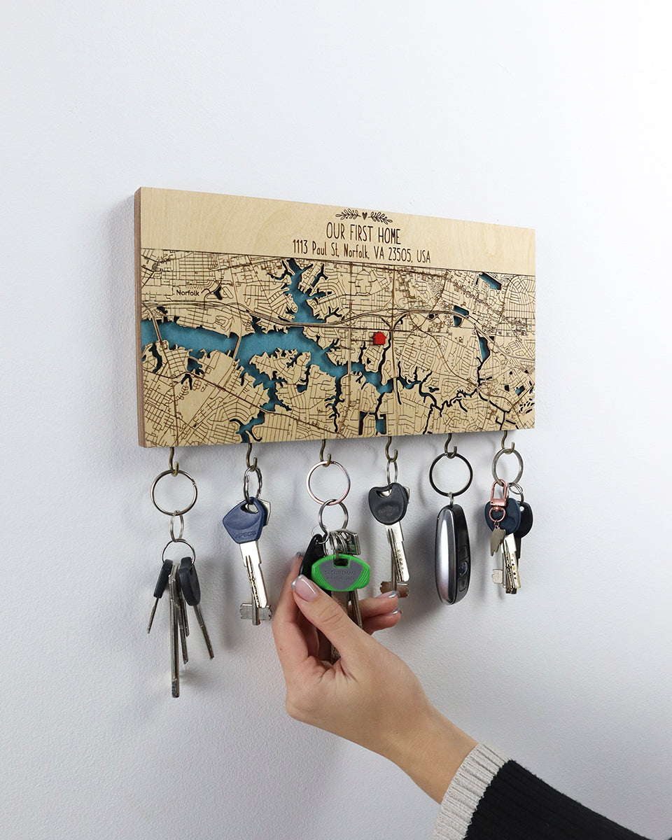 Key holder with keys attached to a map-themed board on a white wall.