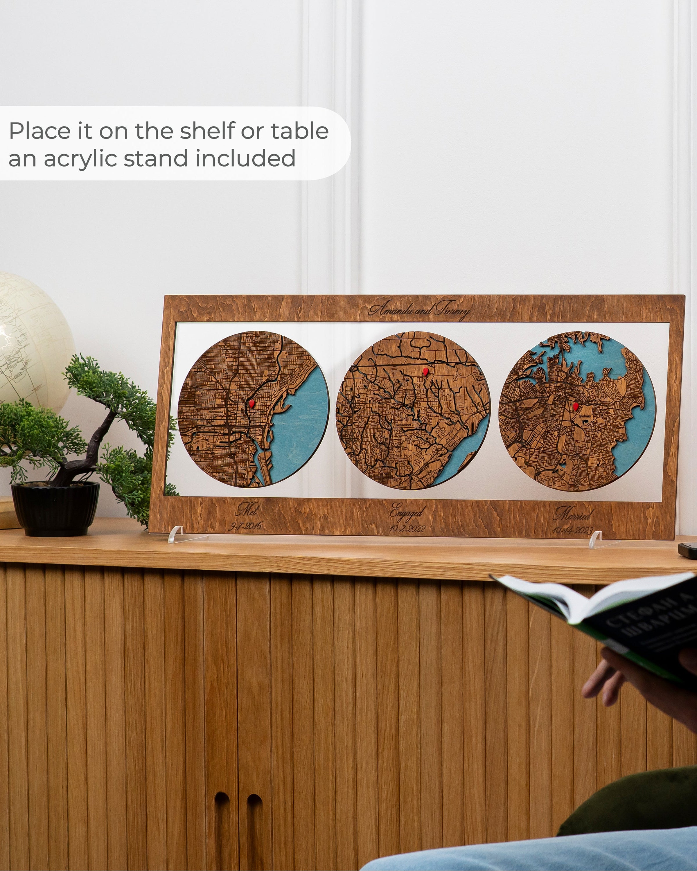 Wooden wall art with three circular designs on a shelf next to a person reading a book.