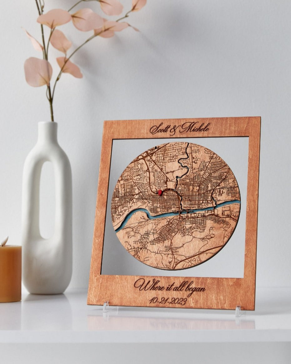 Wooden map plaque with engraved text on a white surface with decorative elements.