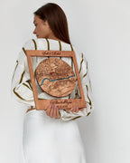 Woman holding a wooden map with engraved text against a white background