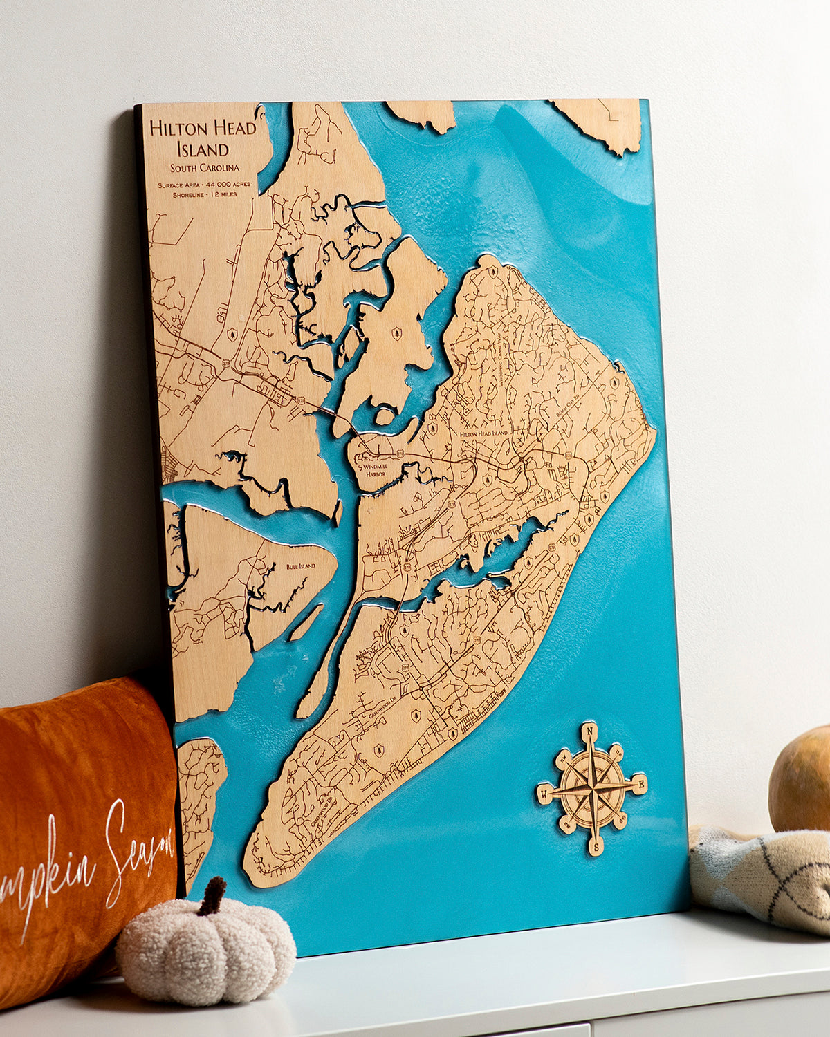 Wooden map of Hilton Head Island on a white surface with decorative items.