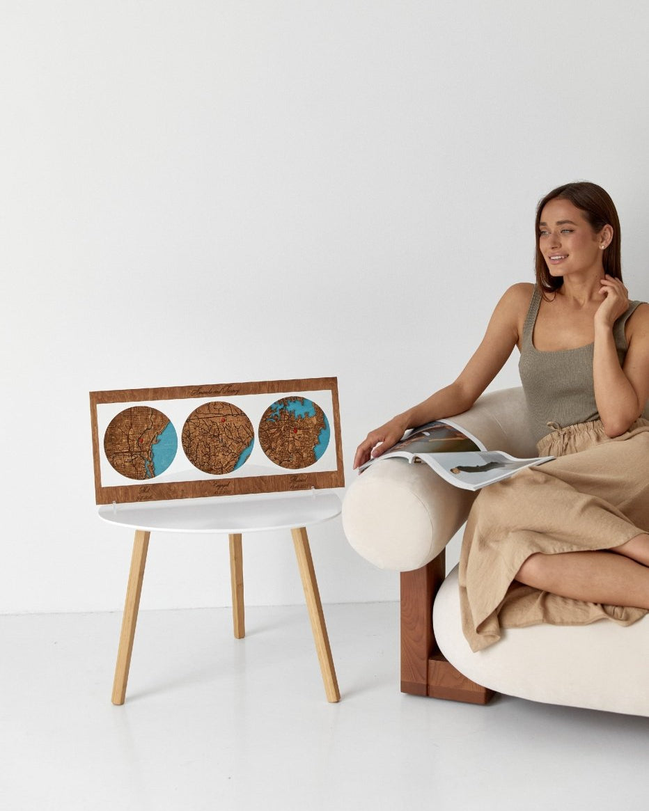 Woman sitting on a modern chair reading a magazine next to a small table with a corkboard surface.