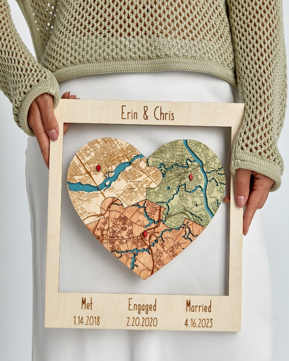 Heart-shaped map with 'Erin & Chris' and dates of significant life events, held by a person wearing a beige sweater.