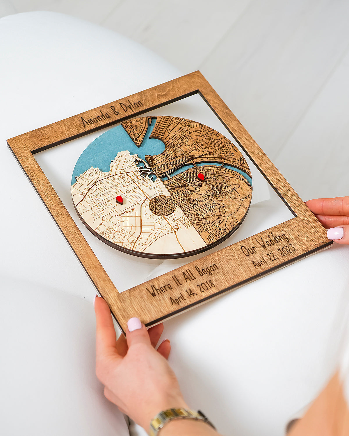Wooden puzzle piece with engraved map and text, held by a hand on a white background
