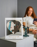 Heart-shaped decorative piece with personalized text on a table, woman using phone in the background