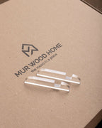 MUR WOOD HOME logo on a cardboard surface with clear acrylic samples.