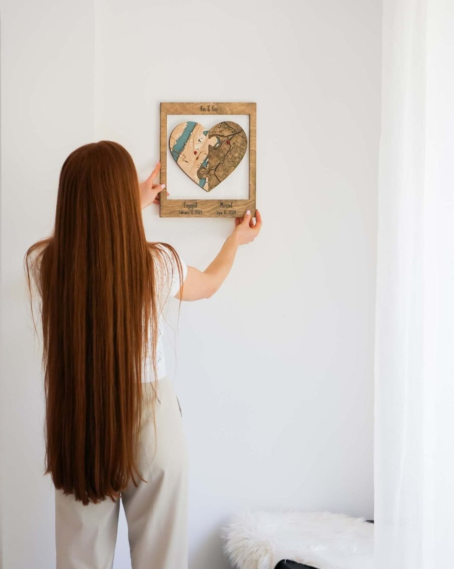 Person hanging a framed heart-shaped artwork on a white wall