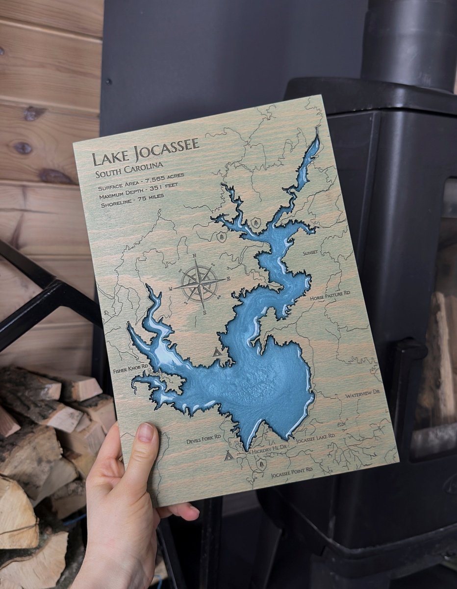 Hand holding a map of Lake Jocassee, South Carolina, against a wooden background.