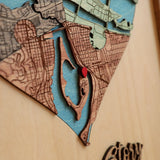 Close-up of layered wooden map sections, blue waterways and a red location marker in a three-part heart map.