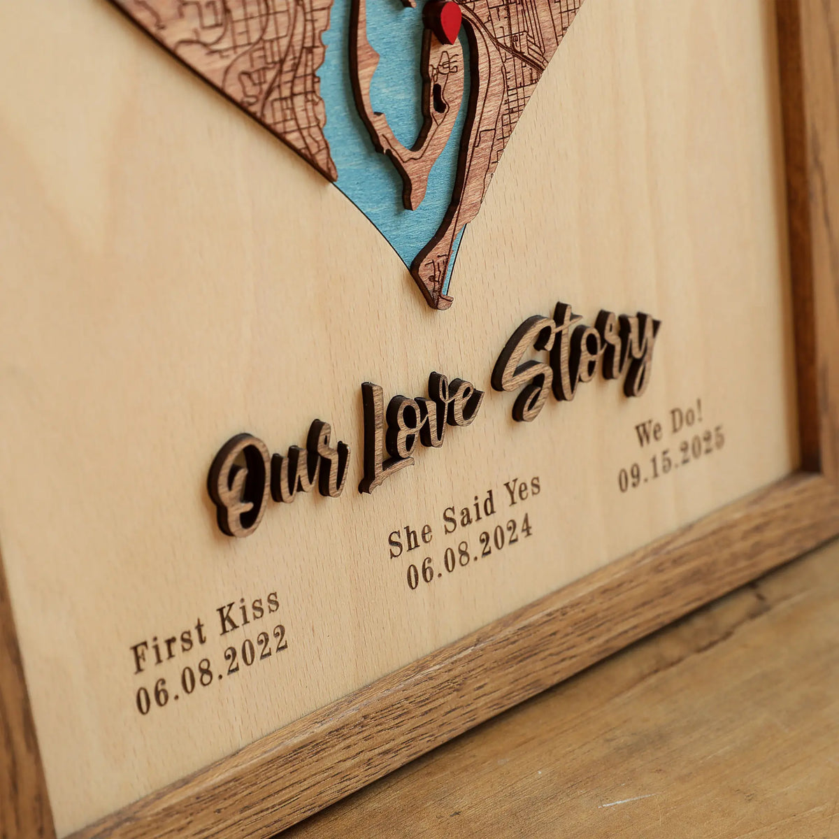 Close-up of raised Our Love Story lettering and personalized dates beneath a wooden heart map.
