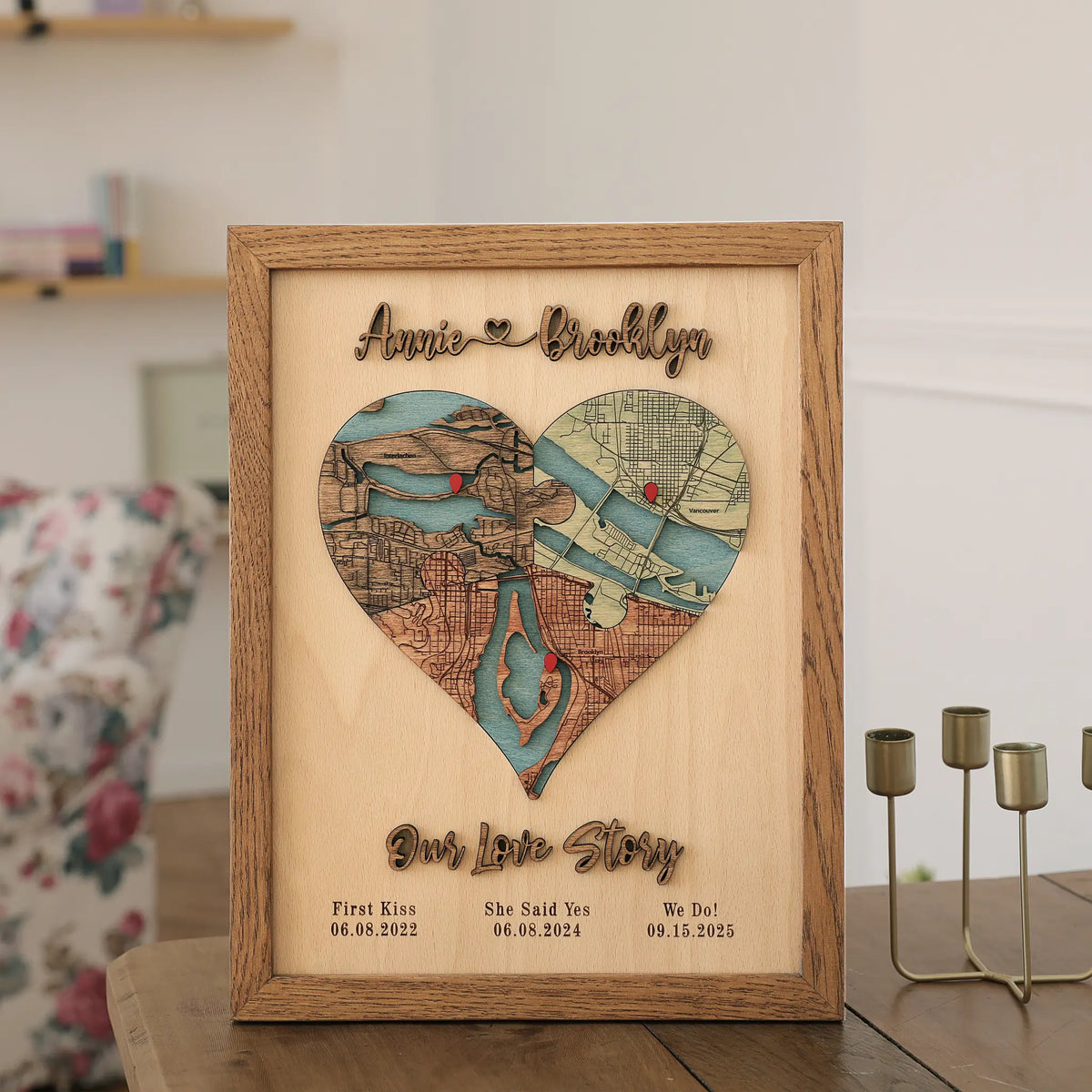 Personalized three-location wooden heart map with Our Love Story lettering displayed on a wooden table at home.