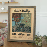Classic Square three-location wooden map in a Grey oak frame displayed on a wooden table beside flowers.