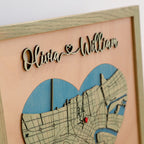 Close-up of raised laser-cut Olivia and William names above a heart-shaped New Orleans map, showing layered wood details and sage oak frame.