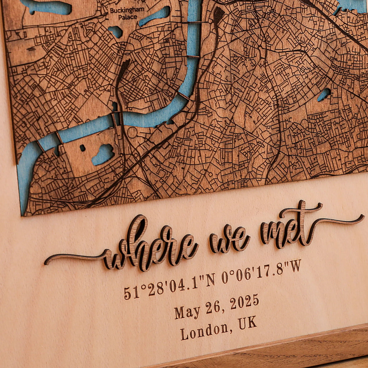 Close-up of raised laser-cut wooden lettering, custom coordinates, date, and London location on a personalized wooden Where We Met map.