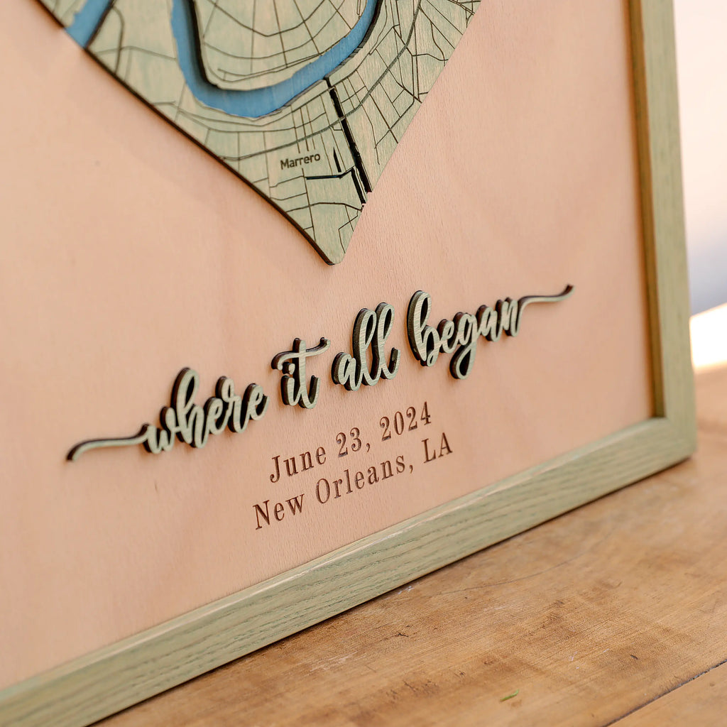 Close-up of raised 3D laser-cut Where It All Began lettering, engraved date, New Orleans location, and sage frame on a personalized wooden anniversary map.