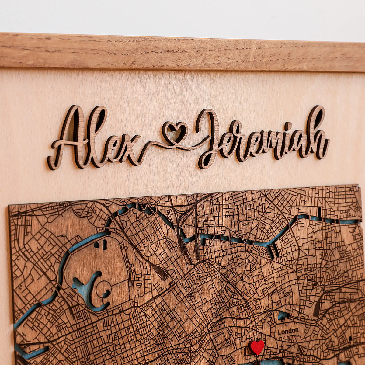Close-up of custom raised wooden names above a detailed London map, showing the 3D lettering and handcrafted layered wood design.