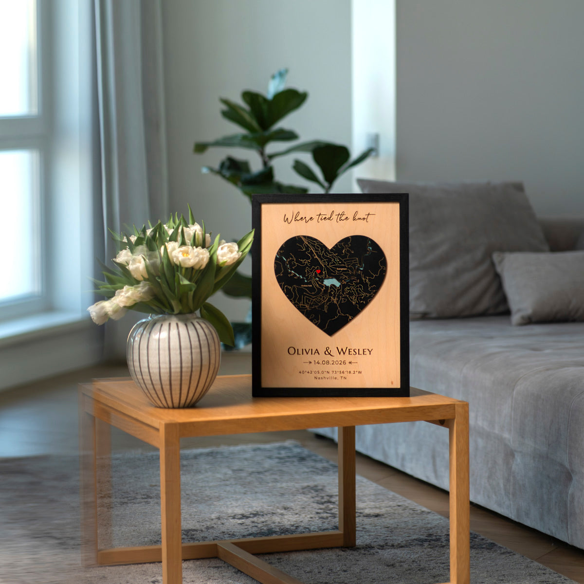 Framed map of the heart with personalized text on a wooden side table in a living room.