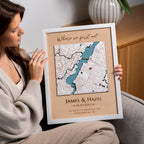 Woman holding a framed map with personalized text, sitting on a couch.
