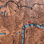 Close-up of detailed laser-cut London map with blue river inlay, engraved streets, and red heart marker showing a meaningful custom location.