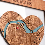 Close-up of heart-shaped personalized new home map with engraved city streets, blue river, and red home location pin