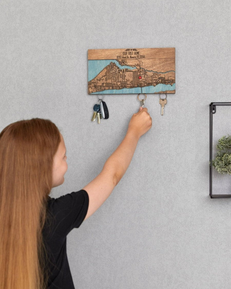 Person using a key holder with a wooden design on a gray wall.