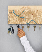 Key holder with map design on a gray wall, showing keys being hung.