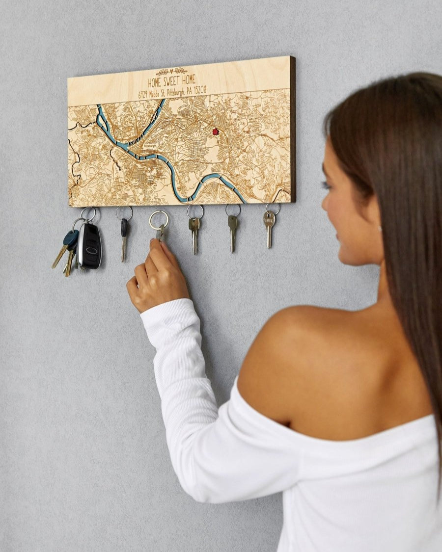 Person using a key holder with a map design on a gray wall
