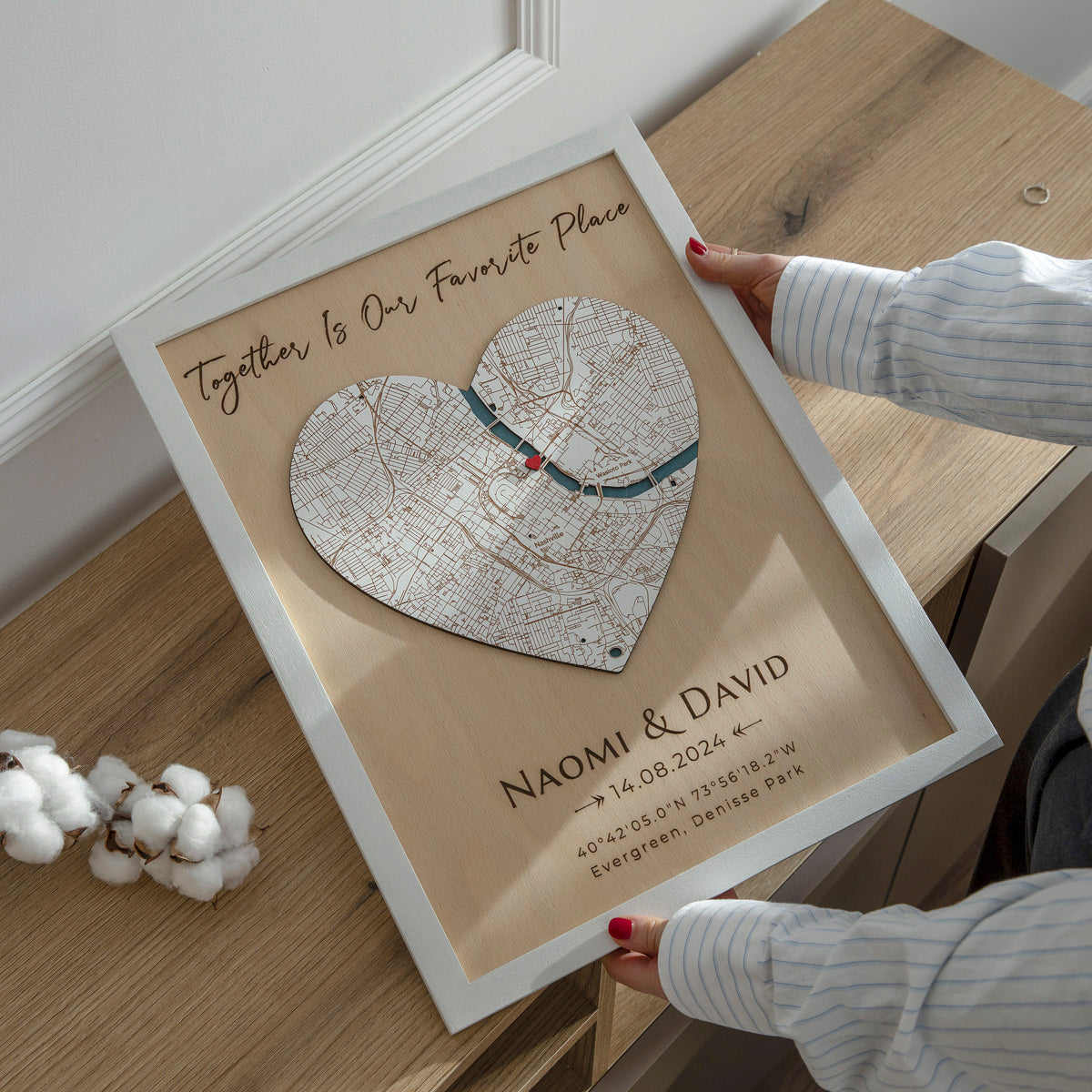 Heart-shaped framed map with personalized text on a wooden surface