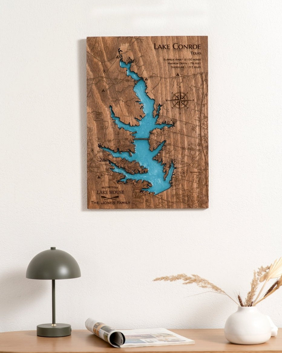 Wooden Lake Conroe map artwork on a wall above a table with decor items.
