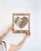 Customized heart-shaped map puzzle in a frame by a person against a wall, featuring two locations with dates for engagement and marriage