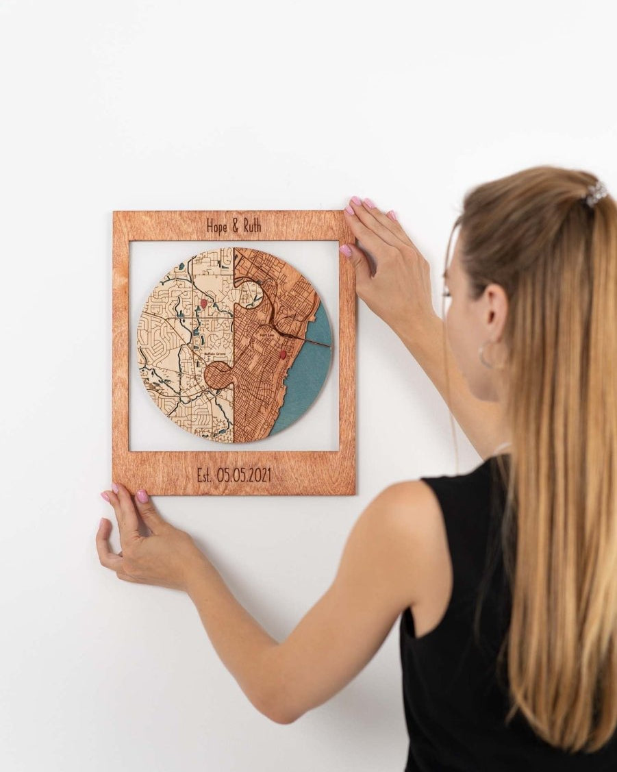 Woman hanging a wooden map artwork on a white wall