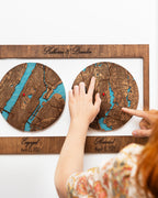 Wooden map location with engraved names and dates, held by a person.